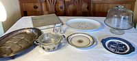 Overview of the vintage serving and dining items on white tablecloth showing all items in lot.