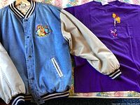 Denim and leather varsity jacket next to purple Winnie the Pooh t-shirt, showing the front side of both