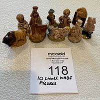 Ten small Wade pottery figures arranged in two rows showing various animal and human figures along with a house figure on a white textured surface.