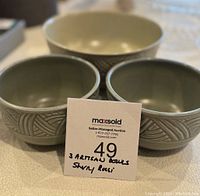 Three ceramic bowls with two smaller gray-green patterned bowls in front and one larger cream bowl in back
