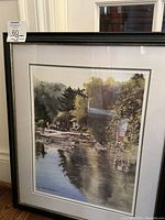Front view of the framed artwork showing a calm lake with a white seaplane docked beside trees and a wooden pier, signed Walter Campbell