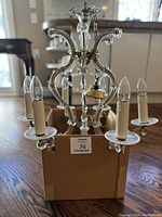 Five-arm chandelier with candle-shaped lightbulbs resting in a box, photo taken to show overall condition and style.