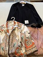 Three ladies blazers/jackets on a surface: black Vanity Fair blazer, paisley patterned blazer, and pink nubby fabric jacket.