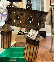 Close-up of the hammered metal circular frame showing decorative cutouts and hanging chain.