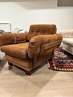 Side angle showing the thick cushioned arms, wooden supports, and ribbed corduroy upholstery