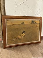Full view of the framed painting showing a girl lying in a field with two houses in the background