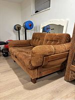 Full side view of the brown corduroy loveseat showing overall shape and condition