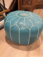 Side/top angled view of teal leather Moroccan pouf showing stitched geometric design and color.