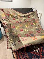 Full view of the quilt draped over a sofa, showing the overall patchwork design and size.