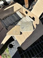 Cardboard box open showing neatly stacked slate tiles approximately 4x4 inches each with a couple tiles resting on top for display, natural colors gray and brown.