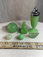 Photo showing all six assorted jade items including a Buddha figurine, round jade ball, pepper shaker, stopper, bead, and small carved bowl lid.
