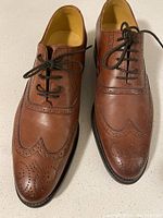 Pair of brown brogue leather dress shoes, laced up, view from above showing wingtip and perforated details.