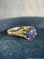 Front view showing round iridescent stone in four-prong setting