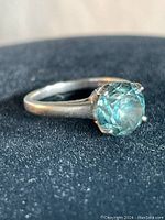 Front view showing round green faceted stone in six-prong white gold setting