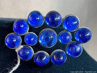 Front view of the vintage blue glass brooch showing the full arrangement of rounded blue glass stones mounted in metal.