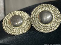 Pair of round earrings with central smooth dome and surrounding twisted rope design, silver color, vintage condition.
