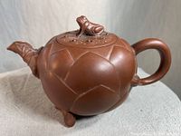 Side view of the Yixing clay teapot showing lotus leaf-patterned body with handle and lotus flower spout.