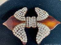 Close up front view of vintage bow hair pin with amber bakelite and clear rhinestones.