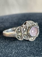 Side angle of the vintage sterling silver ring with pink cabochon stone and marcasite setting, showing texture and stone arrangement.