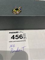 Front view of the 14K gold pendant showing the oval peridot center gemstone surrounded by four colored imitation stones (pink, blue, green, purple) on a textured gold frame.