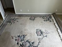 Central view of double door room covered by the beige floral area rug with minor visible wear spots.