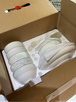 Photo showing the inside of the box with six ceramic bowls and six plates with floral design, all neatly packed in foam padding.