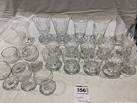 Set of various crystal stemware including sherry glasses, snifters, and parfait glasses arranged on table with measuring ruler visible for scale.