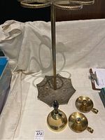 Tall brass umbrella stand with detailed floral pattern base along with the brass bell and candleholders.