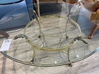 Full top view showing round clear glass surface and brass frame with legs.