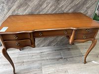 Full view of contemporary styled wooden writing desk by Sebastian Lorenzis. Visible design elements include multiple drawers, curved legs, and metal ring drawer pulls.