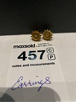 Pair of gold starburst earrings on reference card