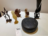 Set of five wooden figures and one stone figure along with a carved round box with West Coast design motifs.