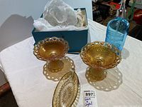 Two amber iridescent carnival glass pedestal compotes, blue spritzer bottle and boxed crystal bowls