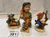 Front view of all three Hummel figurines with visible details and varying heights.