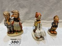 Three Hummel porcelain figurines displayed together showing front view.