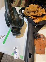 Side view of Craftsman cordless leaf blower and adjacent leather tool belt on table.