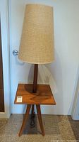 Front view of teak side table with integrated lamp and beige fabric shade