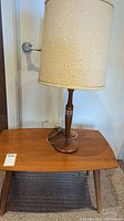 Photo showing the coffee table with the lamp on top, highlighting the wood grain and tapered legs.