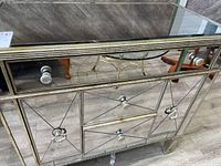 Front view showing six drawers with mirrored panels and glass knobs with geometric line designs.