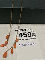 Necklace laid out showing rose gold chain and salmon coral teardrop pendants