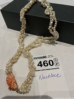 Triple strand freshwater pearl necklace displayed with twisted strands and the coral rose clasp visible.