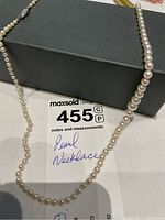 Necklace draped over black box showing full length and note card