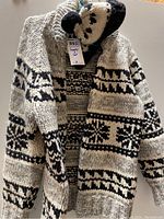 Full view of handmade knitted sweater with black and white patterns and matching hat on top