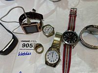 Photo showing various men's wrist watches including smartwatches, a finger watch, and multiple analog wristwatches with different bands, all untested.