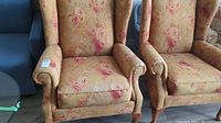 Pair of wing back chairs side by side showing floral upholstery and rolled armrests