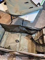 Photo of green fabric yard cart body with some dirt inside, on a white table surface.