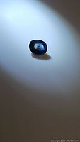 Blue sapphire gemstone shown alone on a white surface, highlighting color and shape.