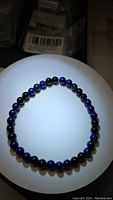 Photo of a stretchy bracelet with alternating round lapis lazuli and black onyx gemstone beads on a flat surface under bright light.