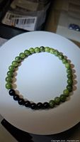 Top view of natural green jade and black onyx bead stretchy bracelet laid flat on a white surface.