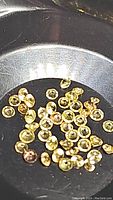 Close-up of multiple small round yellow sapphire gemstones with diamond cut facets, showing color and clarity under lighting.